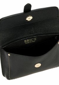 Portafoglio in pelle nera con superficie texture, dotato di chiusura a scatto dorata e dettagli di cucitura leggeri. Interno etichettato "BRIC'S MADE IN ITALY."