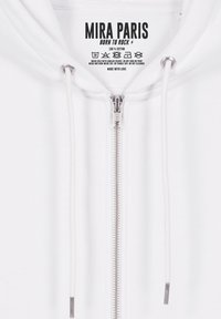 Witte zip-up hoodie gemaakt van 100% katoen. Voorzien van een zilveren rits, koordjes en een bedrukte label met de merknaam en wasinstructies.