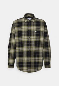 Chemise à manches longues à carreaux verts, noirs et blancs. Dotée d'une fermeture à boutons, d'un col et d'une poche poitrine avec étiquette logo. Tissu en coton.