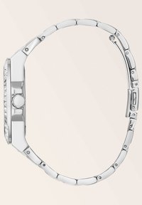 Silberfarbene Uhr mit geometrischem Gehäuse, mit Kristallen besetzter Lünette und linkem Metallarmband. Verfügt über eine einzelne runde Krone zur Einstellung.