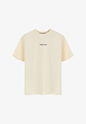 Camiseta de manga corta color crema, hecha de una tela suave, con un cuello redondo y la frase 'POLO CLUB' impresa en negro en el pecho.