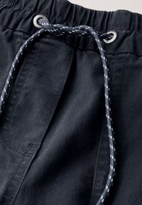 Svarta tygshorts med elastiskt midjeband, med en dragsko i ett kontrasterande mönster av blått och vitt, samt silverfärgade ögla-detaljer.