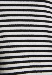 Nahaufnahme eines horizontal gestreiften Stoffes in Schwarz und Weiß mit einer gestrickten Textur.