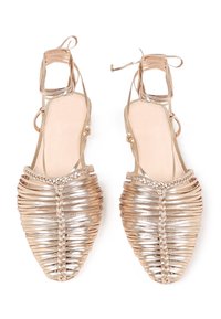 Zlate metalik slingback čevlje z pletenim in črtastim vzorcem, odprto-točkovnim stilom in nežnimi vezalkami okoli gležnja. Ravna podplata, gladka tekstura.