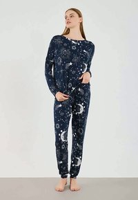 Navy pajama set made of soft fabric, featuring a celestial print with stars and moons, long sleeves, and fitted ankle cuffs.
