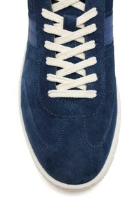 Zapatillas de ante azules con cordones blancos y superficie texturizada. Presenta una suela blanca y rayas laterales azules. Punta redondeada y detalles de costura.