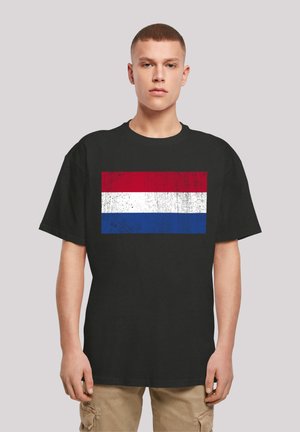Black cotton t-shirt featuring a distressed flag design with horizontal stripes: red, white, and blue. Relaxed fit and short sleeves.