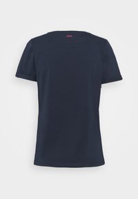 Mörkblå T-shirt med kort ärm gjord av mjuk bomull, med en klassisk rund halsringning och uppvikt ärmslut, samt en liten röd logotyp på baksidan.