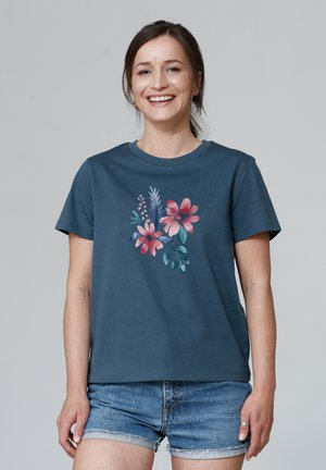 Teal katoenen t-shirt met korte mouwen, versierd met een bloemenontwerp in roze en groene tinten, gecombineerd met denim shorts.