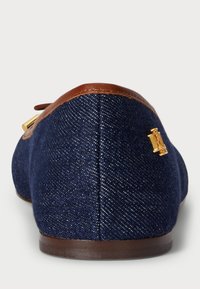 Denim mokaszinok barna bőr díszítéssel a sarkán, arany fém logóval. A felsőrész textúrája szövetmintás.