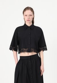 Svart cropped skjorte med spiss krage, kortermet og intrikat blonder trim langs kanten, med knappeåpning foran.