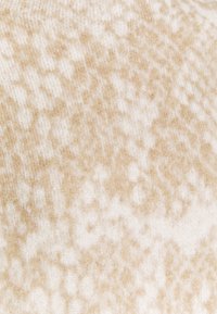Tessuto a maglia in beige e crema con una texture morbida, caratterizzato da un sottile motivo marmorizzato. Ideale per abbigliamento accogliente.