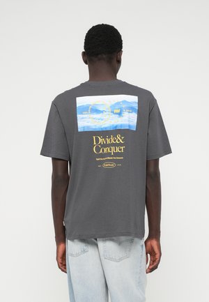 Grå bomulls T-skjorte med korte ermer, med et fjellmotiv på ryggen og teksten "Divide&Conquer" i gult. Løs passform.