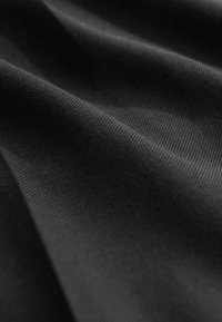 Black fabric with a smooth texture, featuring subtle ribbed patterns. The material is lightweight and flexible, showing gentle folds and creases.