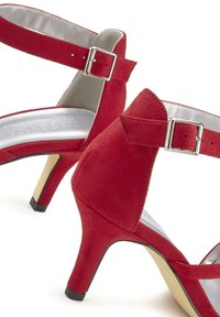 Rote Wildleder-High-Heelsandalen verfügen über einen geschnallten Knöchelriemen, ein silberfarbenes Innenfutter und eine spitze Zehenpartie. Der Absatz hat eine schwarze Gummispitze.