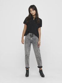 Black short-sleeve top with a keyhole detail, paired with high-waisted, distressed gray jeans, and black ankle boots. Simple, relaxed fit.