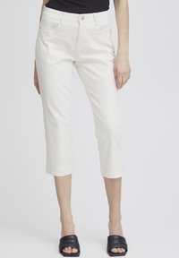Fehér, slim fit szabású, rövidített nadrág öt zsebbel és felgöngyölt szárakkal. Könnyű, sima anyagból készült. Fekete pántos papuccsal párosítva.