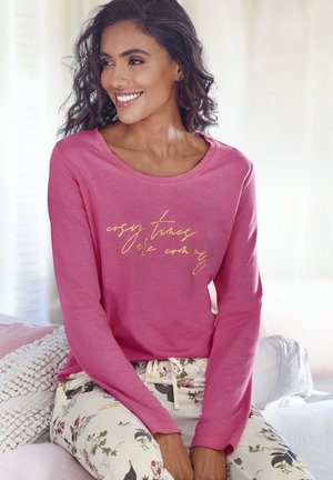 Long-sleeve pink top with gold script text, paired with light-colored patterned pants featuring floral designs. Soft fabric, relaxed fit.