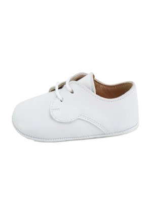 Zapatito de bebé de cuero blanco con suela blanda y cordones blancos, mostrado desde el lado derecho sobre un fondo blanco.