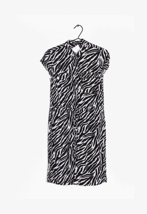 Vestido de manga corta con un estampado de cebra en blanco y negro, cierre frontal de botones, dos bolsillos en el pecho y detalle de cintura fruncida.