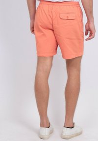 Shorts en coton orange avec une taille élastique et une poche arrière avec bouton. Finition avec un ourlet soigné, adaptés pour un usage décontracté.