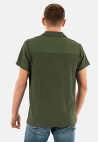 Korte mouwen groene shirt van gestructureerde stof, met een kraag en een modern getailleerd silhouet, gestyled met casual blauwe jeans.