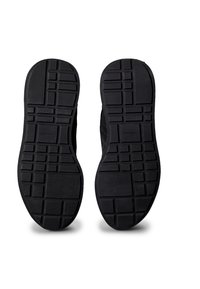 Schwarze Schuhsohlen mit rechteckigen und quadratischen Profilmustern, die nach oben auf einem weißen Hintergrund zeigen.