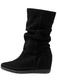 Bottine compensée en daim noir avec un design décontracté, dotée d'un bout arrondi et d'une finition lisse texturée, s'arrêtant au-dessus de la cheville.