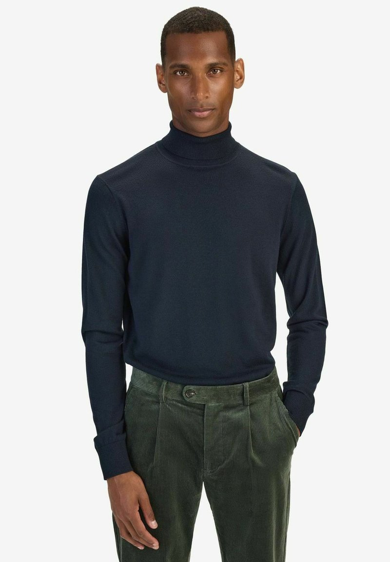 Mörkblå turtlenecktröja med långa ärmar, tillverkad av mjukt tyg. Kombinerad med mörkgröna kordbyxor med två framfickor.