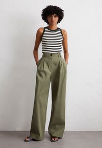 Stripet svart-hvitt tank topp med en tettsittende design kombinert med høy midje, vide olivengrønne bukser, med sidelommer.
