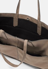 Sac fourre-tout en daim gris avec intérieur noir, doté de deux poignées et d'une poche intérieure, sécurisé par une fermeture à pression sur le dessus.