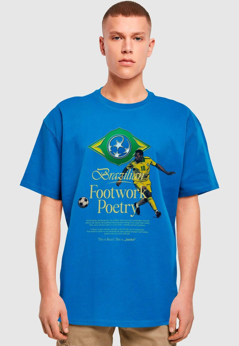 Blå bomulds-T-shirt med et design af det brasilianske flag i gult og grønt, trykt tekst og en illustration af en fodboldspiller.