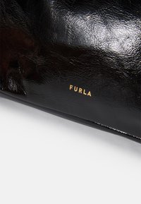 Bolso de mano de charol negro con textura arrugada y logo dorado "Furla" estampado en el lateral. Acabado suave con forma estructurada.