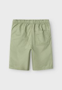 Shorts vert clair avec une taille élastique, une poche arrière et un tissu lisse et léger. Design ajusté avec des bords cousus.