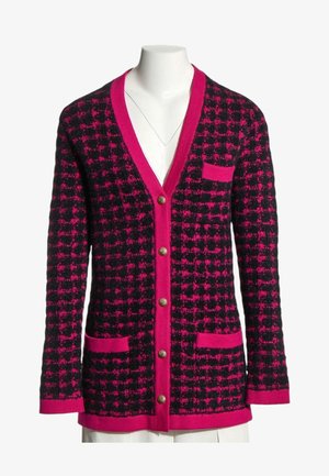 Schwarz und knallpink kariertes Strick-Cardigan mit Frontknöpfen, drei Taschen und tiefem V-Ausschnitt auf einem weißen Schaufensterpuppe-Torso.