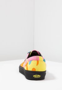Baskets Vans basses avec un motif éclaboussé multicolore en rose, jaune, orange et bleu sur toile et une semelle en caoutchouc noire.