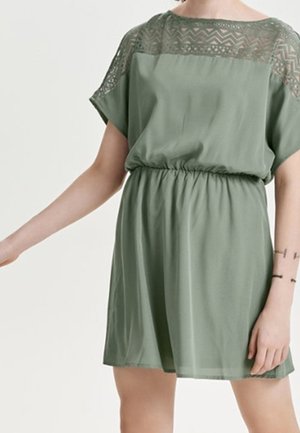 Robe verte à manches courtes, taille élastique et détails en dentelle au niveau du col. Tissu doux et léger avec une silhouette fluide.