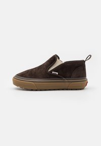Chaussure en daim marron à enfiler avec un design arrondi, une semelle en caoutchouc sable contrastante et une languette arrière. Présente une marque minimale sur le côté.