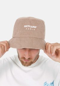 Cappello a secchio in spugna marrone caratterizzato dal logo "SIXTH JUNE PARIS" in bianco, con una larga visiera e una texture morbida.