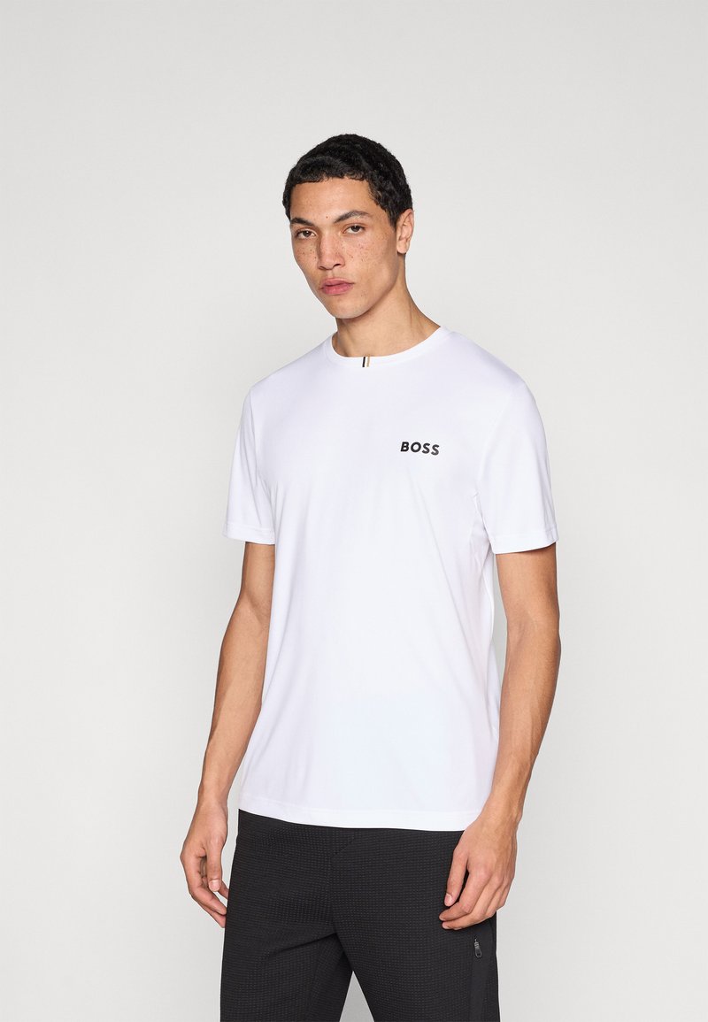 Biele tričko s krátkym rukávom vyrobené z hladkej látky s okrúhlym výstrihom. Na hrudi má čierne logo "BOSS" a prúžkovaný detail.