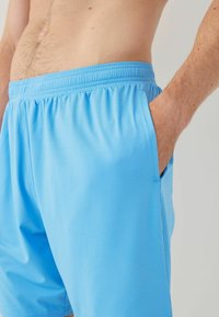Pantaloni scurți sport de culoare albastru deschis, cu o suprafață texturată, talie elastică și buzunare laterale. Proiectați pentru confort și flexibilitate.