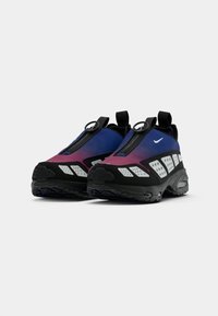 Baskets Nike présentant un dégradé de violet et de bleu avec des accents noirs, des panneaux en mesh, une languette circulaire et une semelle texturée.