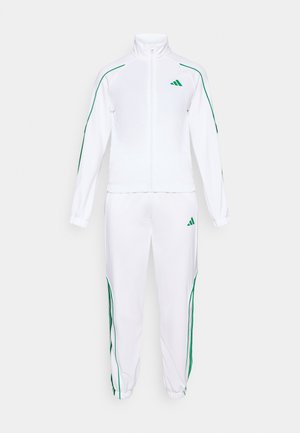 Fato de treino branco feito de tecido suave, com riscas laterais verdes, uma jaqueta com fecho éclair e punhos elásticos nas calças. Logotipo da Adidas na jaqueta.