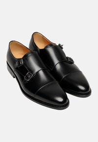Schwarze Leder-Doppel-Monk-Schnürschuhe mit glatter Textur, spitzem Zehenbereich und silberfarbigen Schnallen. Verfügt über kontrastierende Nähte entlang der Sohle.