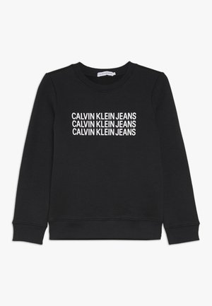 Černá mikina vyrobená z bavlny, s kulatým výstřihem a pružnými manžetami. Na přední straně je opakovaný bílý text "CALVIN KLEIN JEANS".