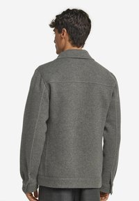 Grå ullblandad jacka med krage, rak passform, knäppte ärmar och synliga sömdetaljer på ryggen.