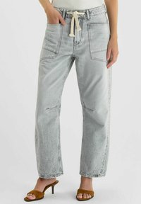 Jean gris clair à jambes larges en denim, avec taille à cordon, deux poches avant et texture légèrement délavée.