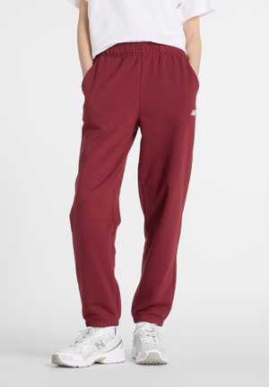 Bordeauxkleurige sweatpants met een elastische tailleband, zijzakken en geribbelde mouwen. Bevat een klein wit logo op de linker bovenbeen.