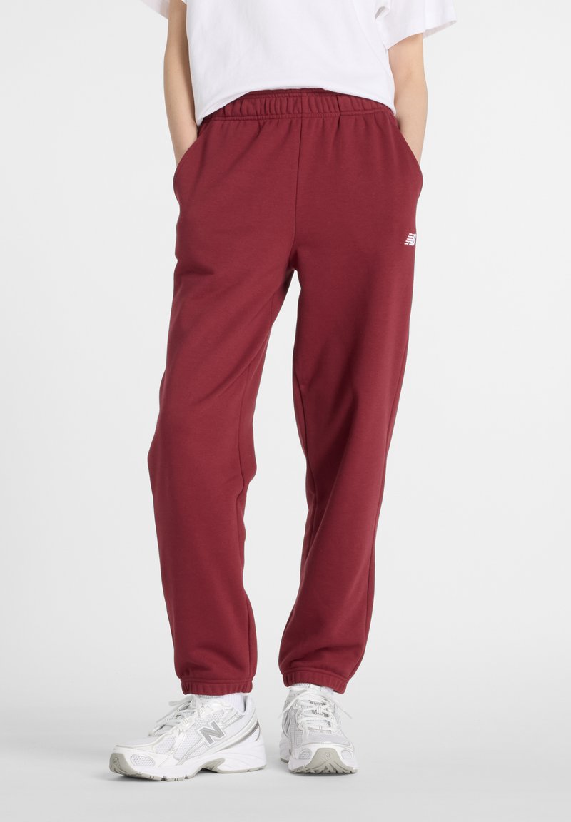 Burgundy sweatpants med elastisk midja, sidfickor och ribbade muddar. Har en liten vit logotyp på vänster lår.