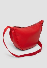 Czerwona skórzana torba na ramię o gładkiej fakturze, zaokrąglonym kształcie i zamknięciu na zamek. Posiada szeroki, regulowany materiałowy pasek.